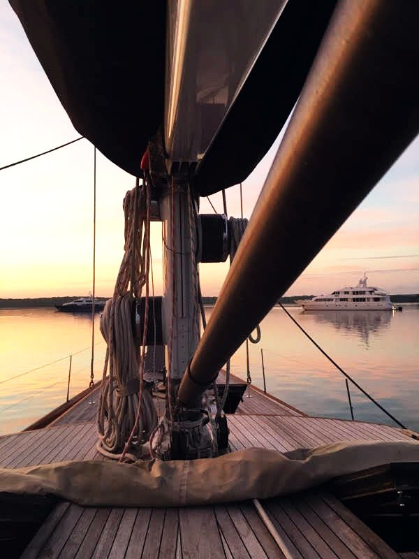 The bow and furled headsail at dusk, teak foredeck in low light