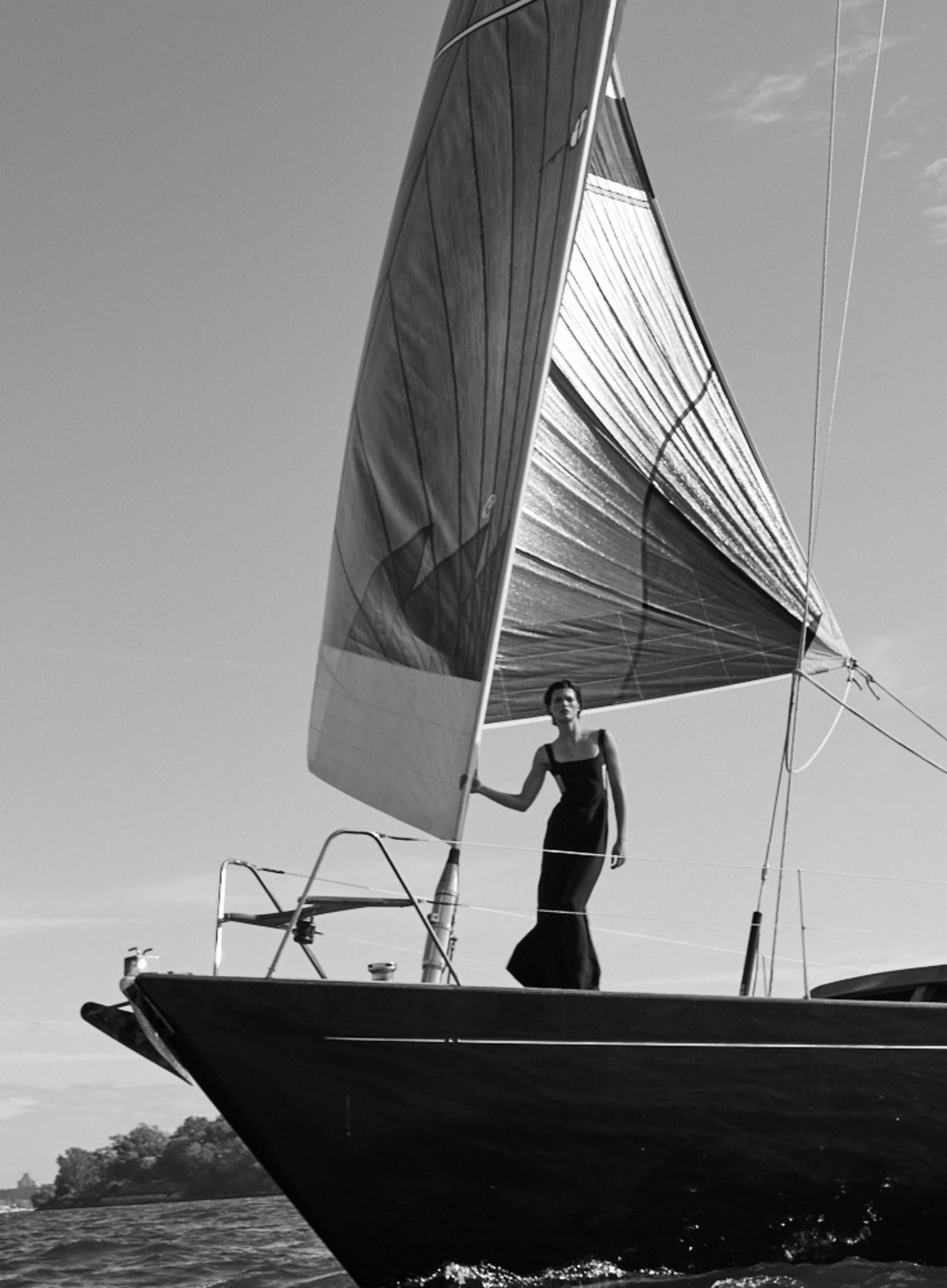 A figure standing at the bow of Lauren L under sail, photographed in black and white
