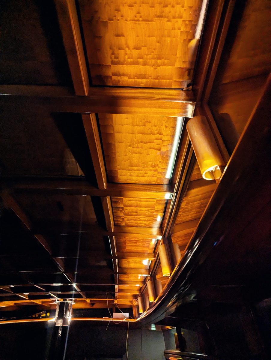 The mahogany deckhead above the saloon, lit warm by shaded fittings