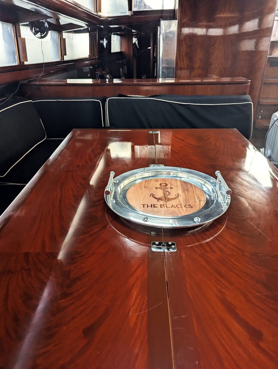 The mahogany dining table in the deckhouse, with a polished anchor tray at its centre